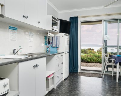The modern kitchen of Bayview Apartment at Emu Bay Holiday Homes, equipped with sleek appliances, ample counter space, and stylish decor, offering guests a functional and inviting space to prepare meals and gather together