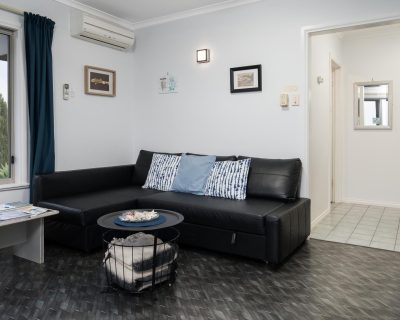 The inviting living room of Bayview Apartment at Emu Bay Holiday Homes, furnished with cosy seating, warm lighting, and tasteful decor, providing a comfortable and relaxing space for guests to unwind and enjoy the Emu Bay.