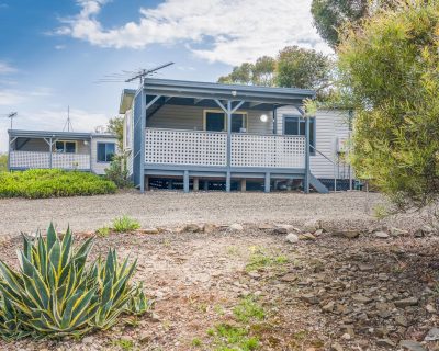 Rustic Cabin 1 and 2 at Emu Bay Holiday Homes, nestled in a serene natural setting with rustic exterior features and surrounded by lush greenery, providing guests with a cosy and tranquil retreat.