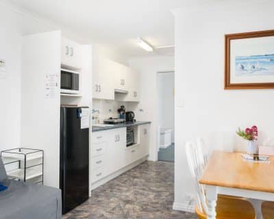 A bright and modern kitchen inside Cottage 3 at Emu Bay Holiday Homes, featuring sleek appliances, ample counter space, and stylish decor, providing a functional and inviting environment for guests to prepare meals and gather together.