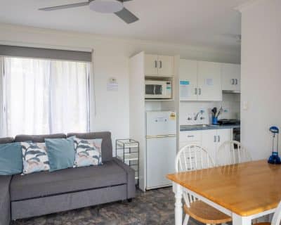 The cosy living room of Cottage 3 at Emu Bay Holiday Homes, adorned with comfortable furnishings, warm lighting, and tasteful decor, providing a welcoming space for guests to relax and unwind after a day of exploring.