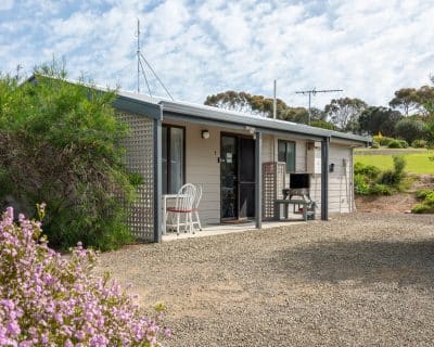 he outdoor patio of Cottage 4 at Emu Bay Holiday Homes, featuring comfortable seating and surrounded by lush greenery, providing a tranquil and inviting space for guests to relax and enjoy the natural surroundings.