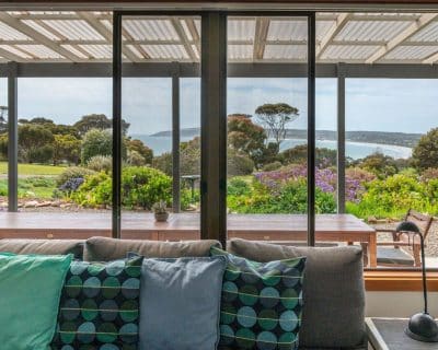 The welcoming living room of Jireh House at Emu Bay Holiday Homes, adourned with comfortable furnishings, warm lighting, and tasteful decor, offering a cosy space for relaxation and socialising.