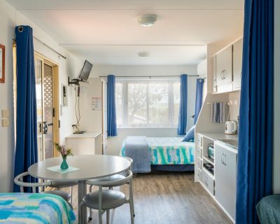 The cosy bedroom of Rustic Cabin 1 and 2 at Emu Bay Holiday Homes, featuring a comfortable bed, soft linens, and rustic decor, providing guests with a warm and inviting space to rest and recharge amidst the serene surroundings.