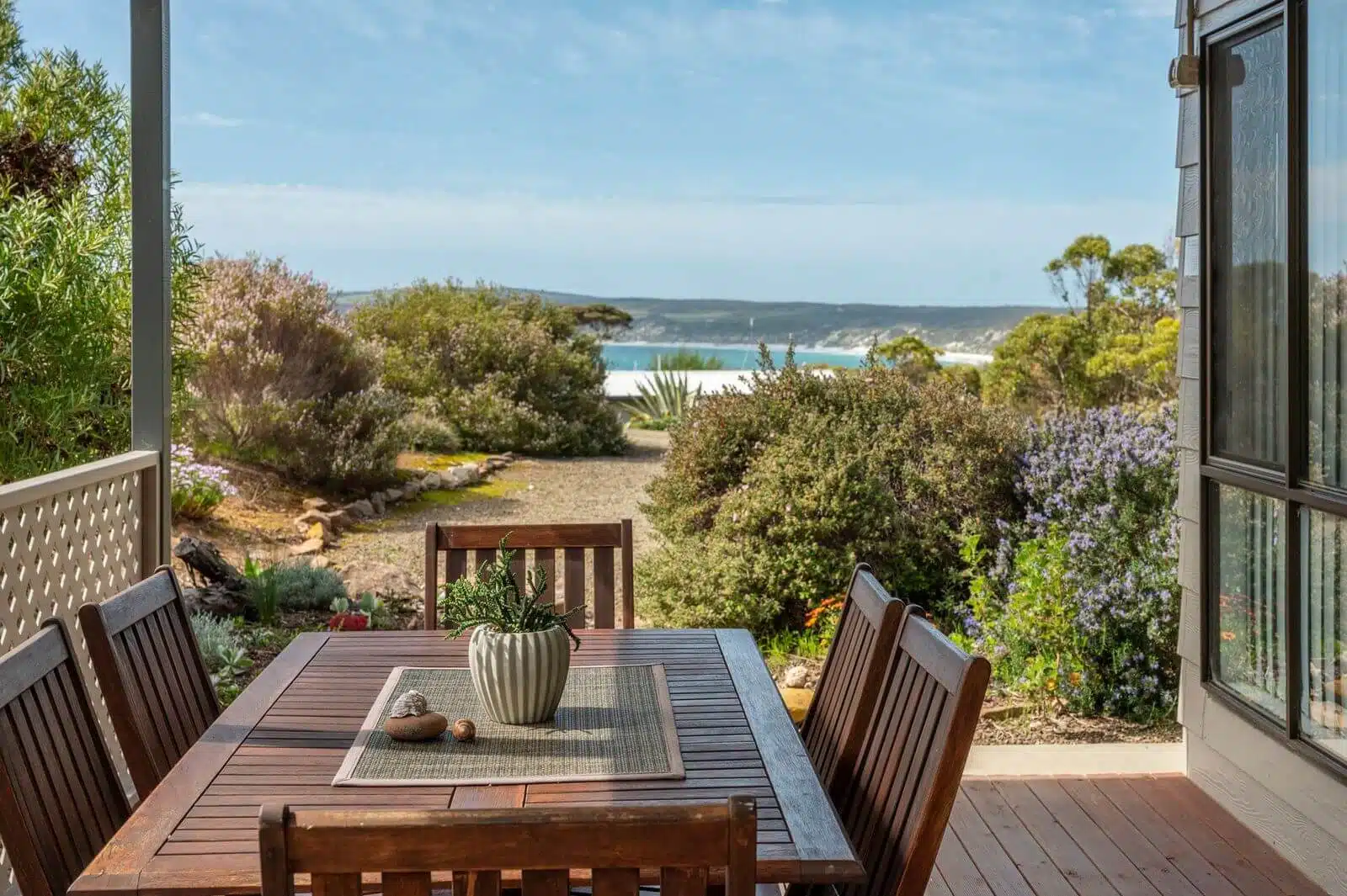 Shalom House Patio - Emu Bay Accommodation A serene patio at Shalom House, holiday home in Emu Bay, Kangaroo Island with comfortable outdoor furniture surrounded by birds chirping and koalas in the trees, overlooking a tranquil bay.