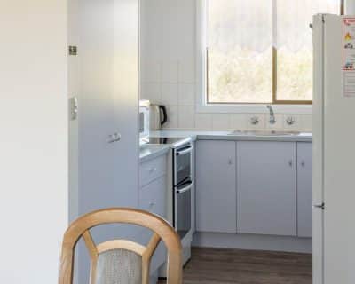 The modern kitchen of Shalom House at Emu Bay Holiday Homes, featuring stainless steel appliances, sleek countertops, and ample cabinet space, providing a stylish and functional area for cooking and dining.