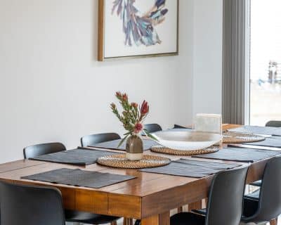 In the dining area of Amani House, warmth and sophistication intertwine seamlessly, creating an ambiance that delights the senses and beckons guests to linger in each moment. The table, meticulously set with elegant dinnerware, gleams softly under the gentle glow of ambient lighting, casting a welcoming aura over the space.