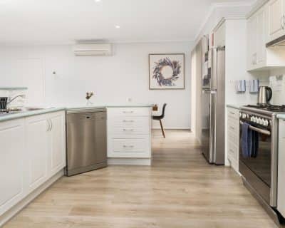 Spacious and fully equipped self-catering kitchen at Amani House, Emu Bay Kangaroo Island. Recently renovated, it features modern appliances, ample counter space, and large windows that offer natural light and stunning views, making catering a delight for groups of 2-9 guests.